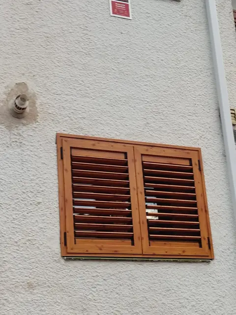 Contraventanas mallorquinas de lamas en acabado imitación madera en una fachada